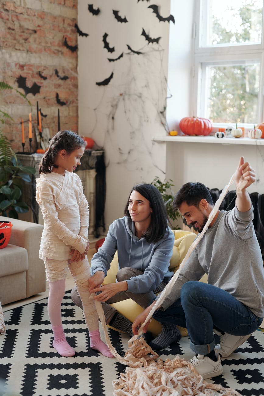 parents helping their child dress up a mummy costume