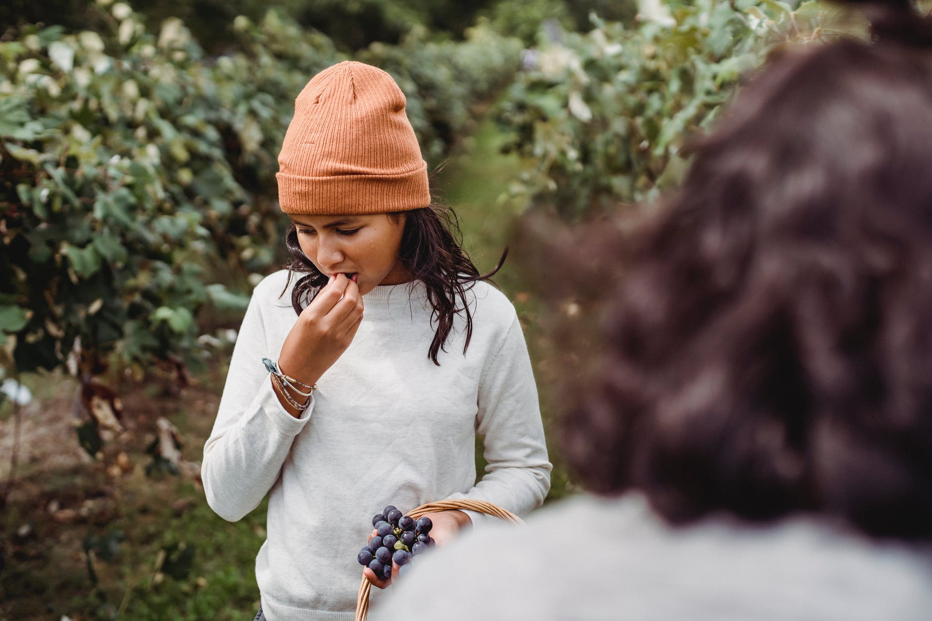 ethnic girl trying delicious grapes in garden