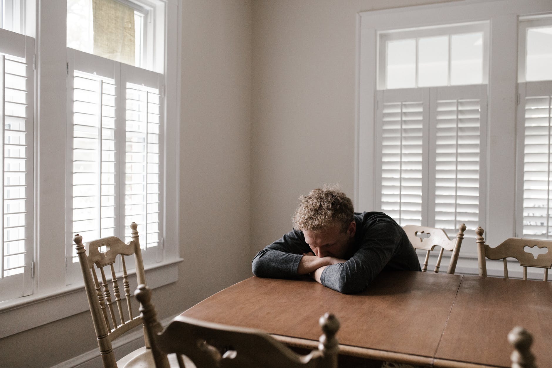 man in gray long sleeve shirt sitting on brown wooden chair