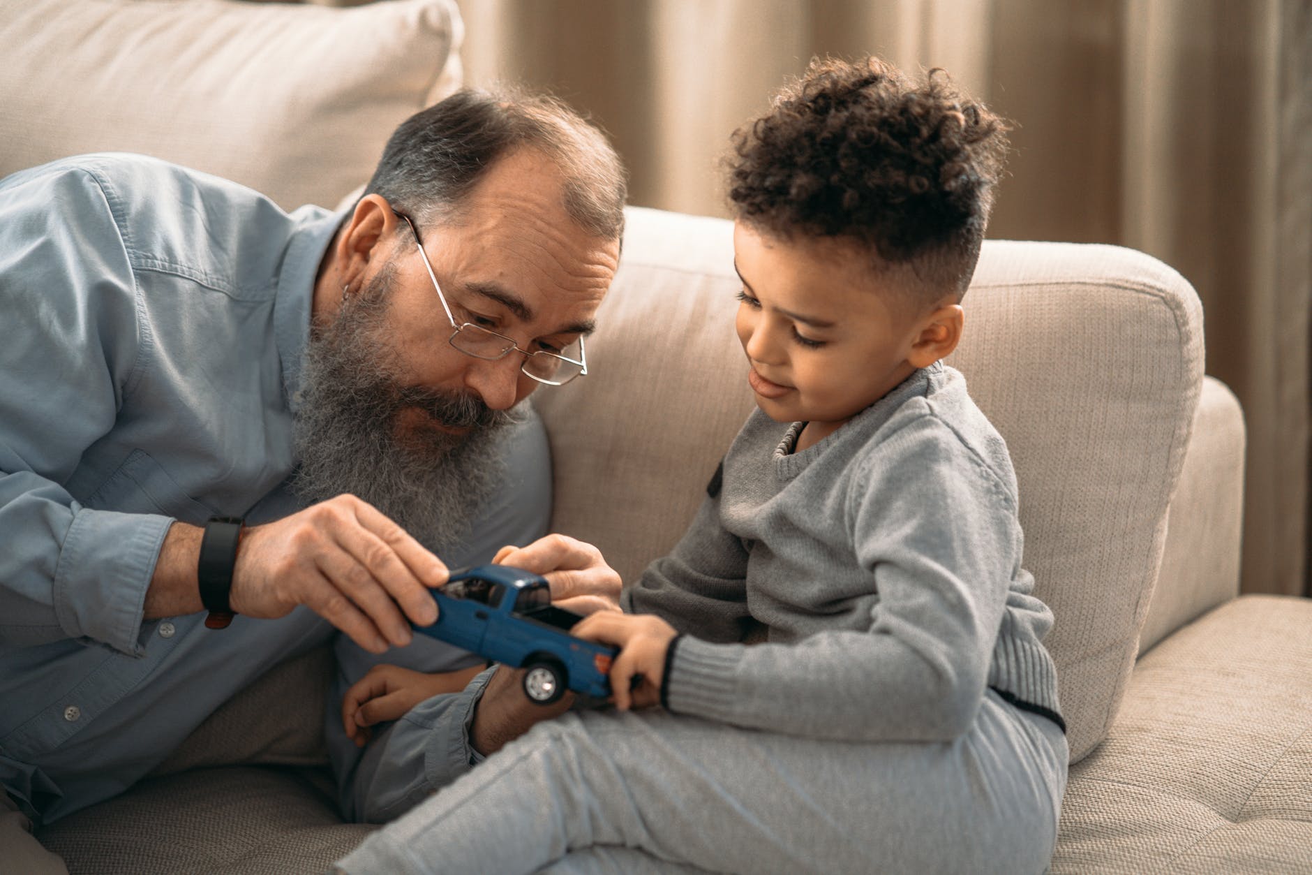 boy in gray sweater holding blue toy car