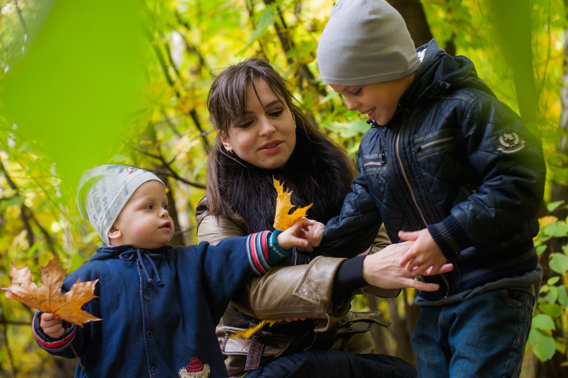 two boys and woman surrounded green plants